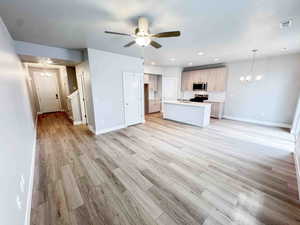 Kitchen featuring a chandelier, open floor plan, light countertops, an island with sink, and recessed lighting