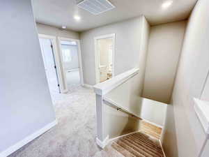 Hallway with an upstairs landing, light carpet, and recessed lighting
