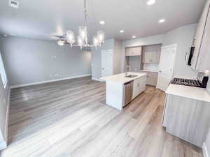 Kitchen with a center island with sink, light stone counters, decorative light fixtures, open floor plan, and stainless steel appliances
