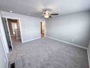 Unfurnished bedroom featuring light carpet, a textured ceiling, and ceiling fan
