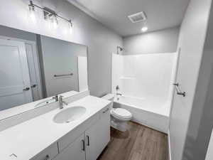 Full bathroom featuring tub / shower combination, dark wood-style floors, vanity, and a textured ceiling