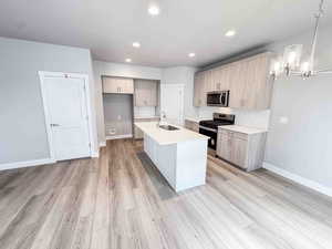 Kitchen featuring stainless steel appliances, light stone countertops, recessed lighting, a kitchen island with sink, and light wood-type flooring