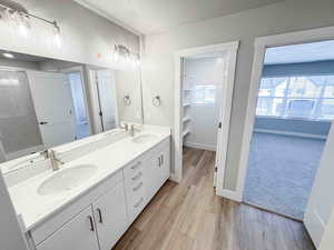Full bathroom with a textured ceiling, light wood finished floors, and double vanity
