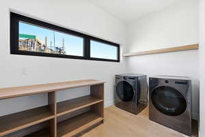 Laundry room featuring washer and clothes dryer and light wood finished floors