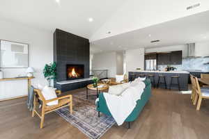 Living area featuring dark wood finished floors, a fireplace, and vaulted ceiling