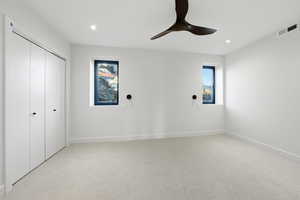 Unfurnished bedroom with light carpet, a ceiling fan, a closet, and recessed lighting