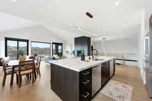 Kitchen with a mountain view, modern cabinets, open floor plan, a kitchen island with sink, and light wood finished floors