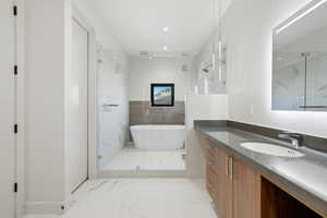 Full bathroom with a freestanding tub, vanity, a marble finish shower, and light marble finish flooring