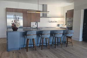 Kitchen with modern cabinets, a center island with sink, light wood-style floors, and a breakfast bar