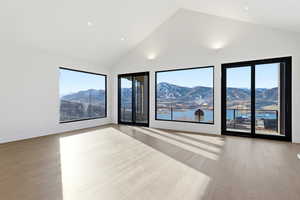 Unfurnished room featuring high vaulted ceiling, light wood finished floors, and a mountain view