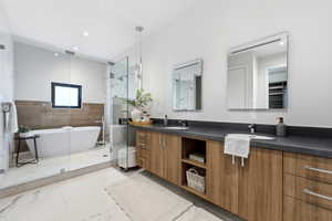 Bathroom with double vanity, a marble finish shower, a freestanding tub, light marble finish floors, and recessed lighting