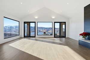 Unfurnished room featuring wood finished floors, high vaulted ceiling, and a mountain view