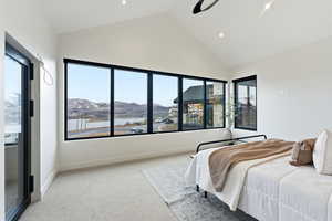 Bedroom with light carpet, access to outside, vaulted ceiling, ceiling fan, and a water and mountain view