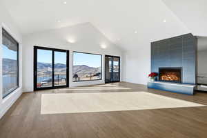 Unfurnished living room featuring a mountain view, a tile fireplace, light wood-type flooring, and high vaulted ceiling