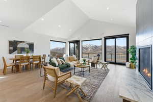 Living area featuring a mountain view, a large fireplace, a high ceiling, light wood-type flooring, and recessed lighting