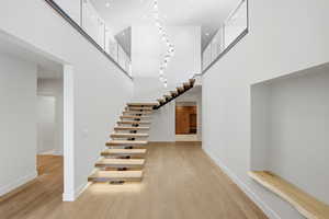 Stairs with a high ceiling, wood finished floors, and recessed lighting