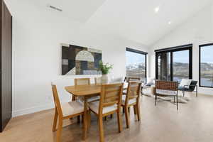 Dining area featuring light wood-style floors, vaulted ceiling, and a water and mountain view