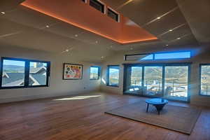 Unfurnished living room with hardwood / wood-style flooring, healthy amount of natural light, a towering ceiling, and a mountain view