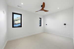 Empty room featuring healthy amount of natural light, light carpet, a ceiling fan, and recessed lighting
