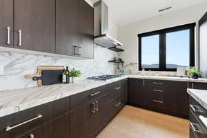 Kitchen with dark wood finish cabinetry, backsplash, light wood-style flooring, and modern cabinets
