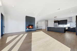 Unfurnished living room with a fireplace, light wood finished floors, recessed lighting, and high vaulted ceiling