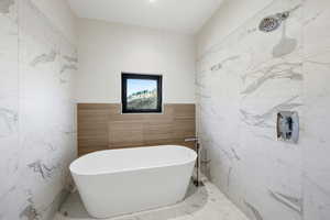 Bathroom featuring a soaking tub and marble tiled flooring