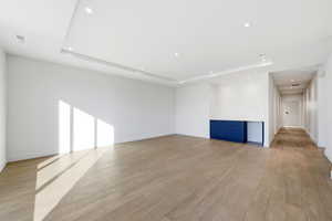 Empty room with a raised ceiling, light wood finished floors, and recessed lighting