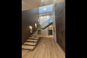 Staircase featuring a towering ceiling, wood finished floors, and recessed lighting