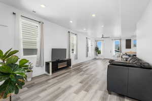Living room with a glass covered fireplace, recessed lighting, light wood-style flooring, and ceiling fan