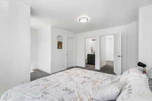 Bedroom with dark carpet and connected bathroom