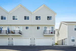 Back of house with a balcony and an attached garage