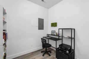 Home office with wood finished floors and electric panel
