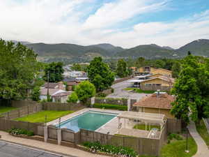 Community pool with a mountain view, a fenced backyard, and a patio area