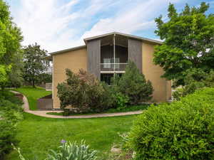 Rear view of property with a yard and a balcony