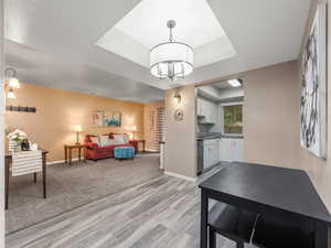 Living area featuring a raised ceiling, light wood-style floors, and a chandelier