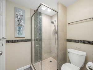 Full bath featuring toilet and a shower stall