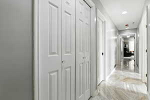Hallway with light marble finish floors and recessed lighting