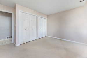 Unfurnished bedroom with two closets and light carpet