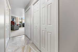 Primary bedroom hall with light marble flooring and hall, walk-in and storage closets.