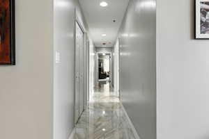 Hallway view from front room to primary. Hallway with recessed lighting and light marble finish floors