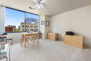 Carpeted home office with a view of city and ceiling fan