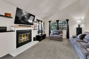 Carpeted living room featuring a tile fireplace and high vaulted ceiling
