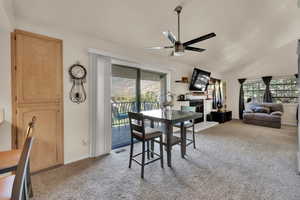 Dining room featuring light carpet, vaulted ceiling, and ceiling fan