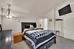 Bedroom featuring lofted ceiling and light colored carpet