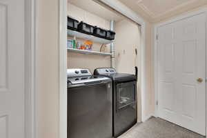Laundry room with separate washer and dryer and light carpet