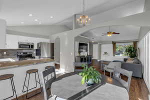 Dining room with arched walkways, lofted ceiling, a ceiling fan, dark wood-style floors, and a chandelier