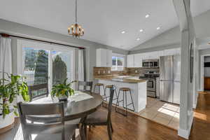 Dining space featuring lofted ceiling, light wood-type flooring, recessed lighting, and a chandelier