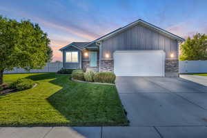 Single story home with board and batten siding, an attached garage, driveway, and brick siding
