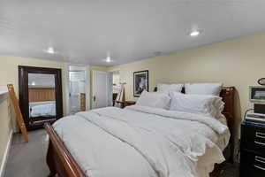 Carpeted bedroom featuring connected bathroom and recessed lighting