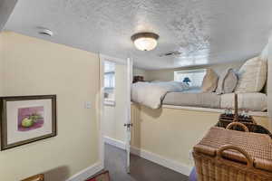 Bedroom featuring multiple windows, a textured ceiling, and a textured wall